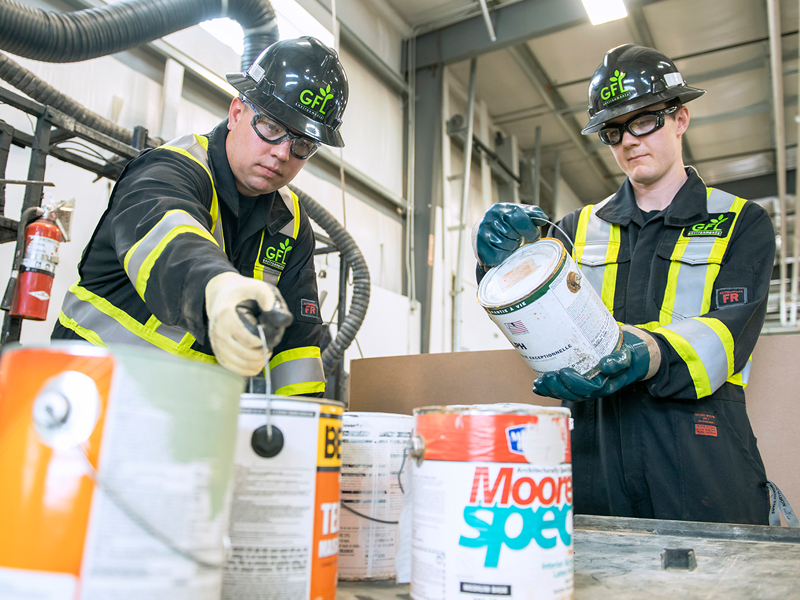 2 GFL employees examining hazardous waste and cans of materials